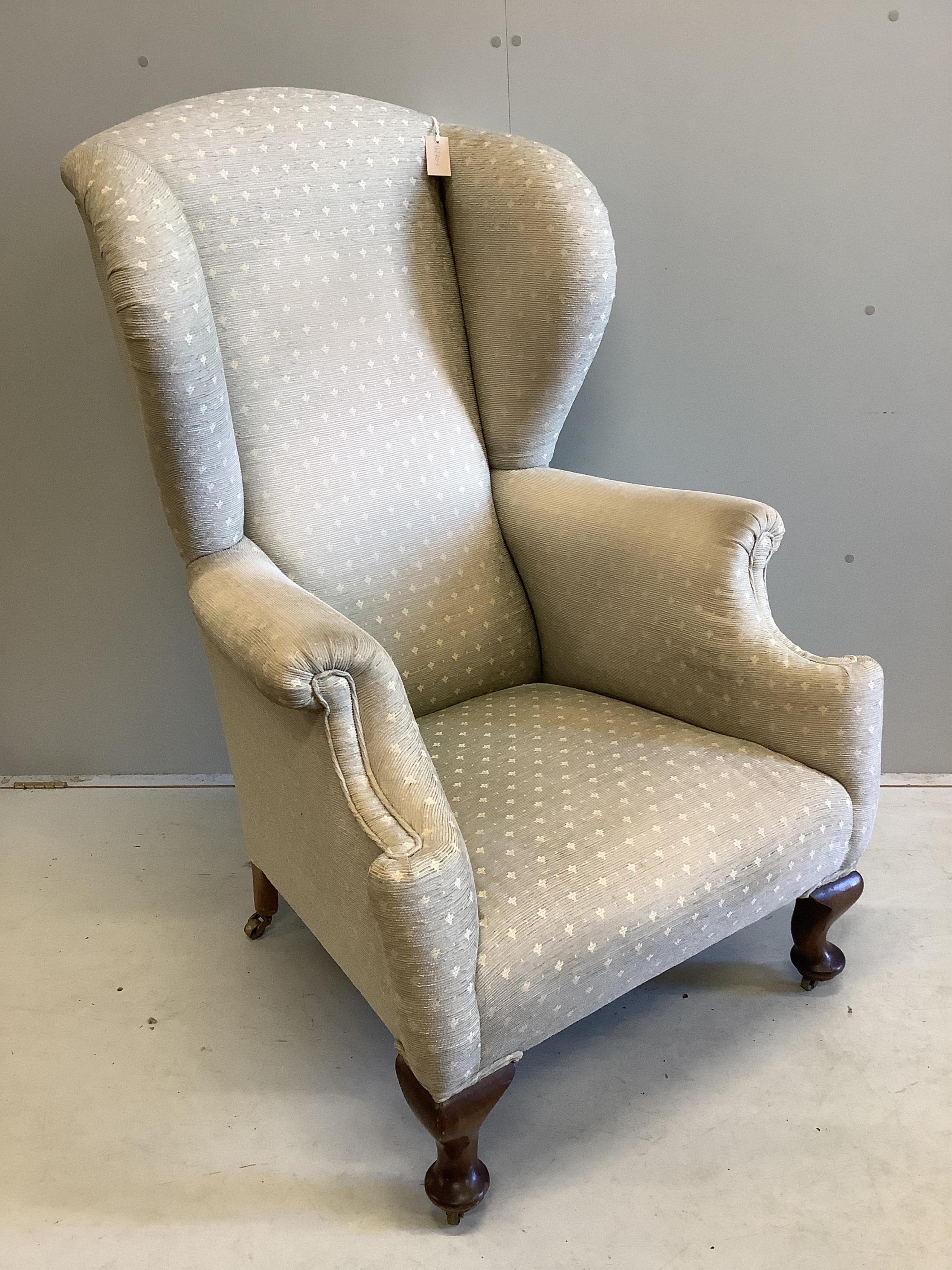 An early 20th century upholstered wing armchair, width 80cm, depth 80cm, height 124cm. Condition - fair